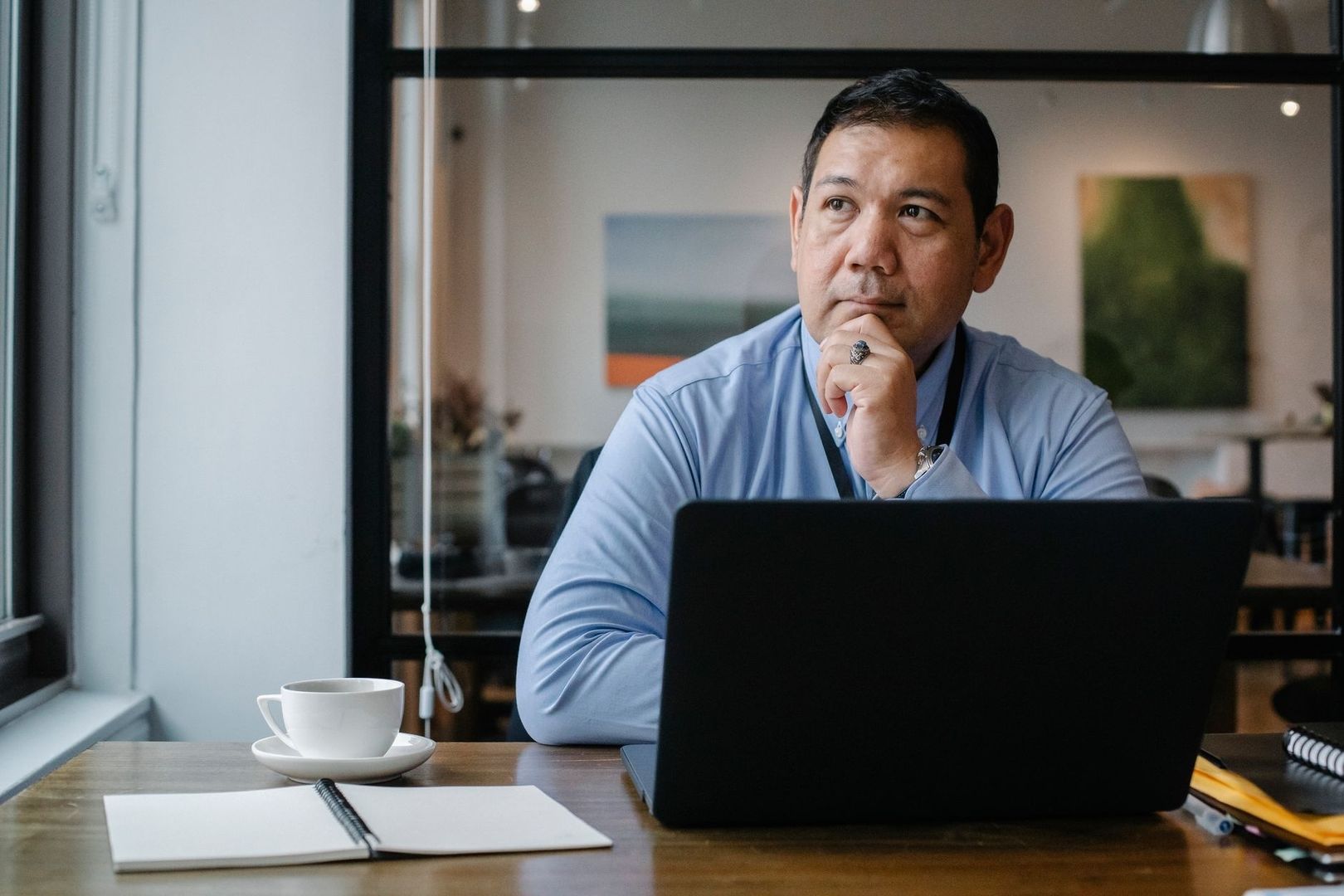 Eftertänksam man arbetar vid laptop i hemmakontor